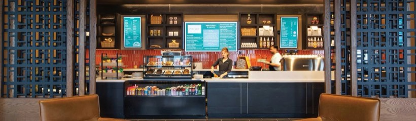 A hotel lobby cafe counter with pastry cases and a espresso bar.